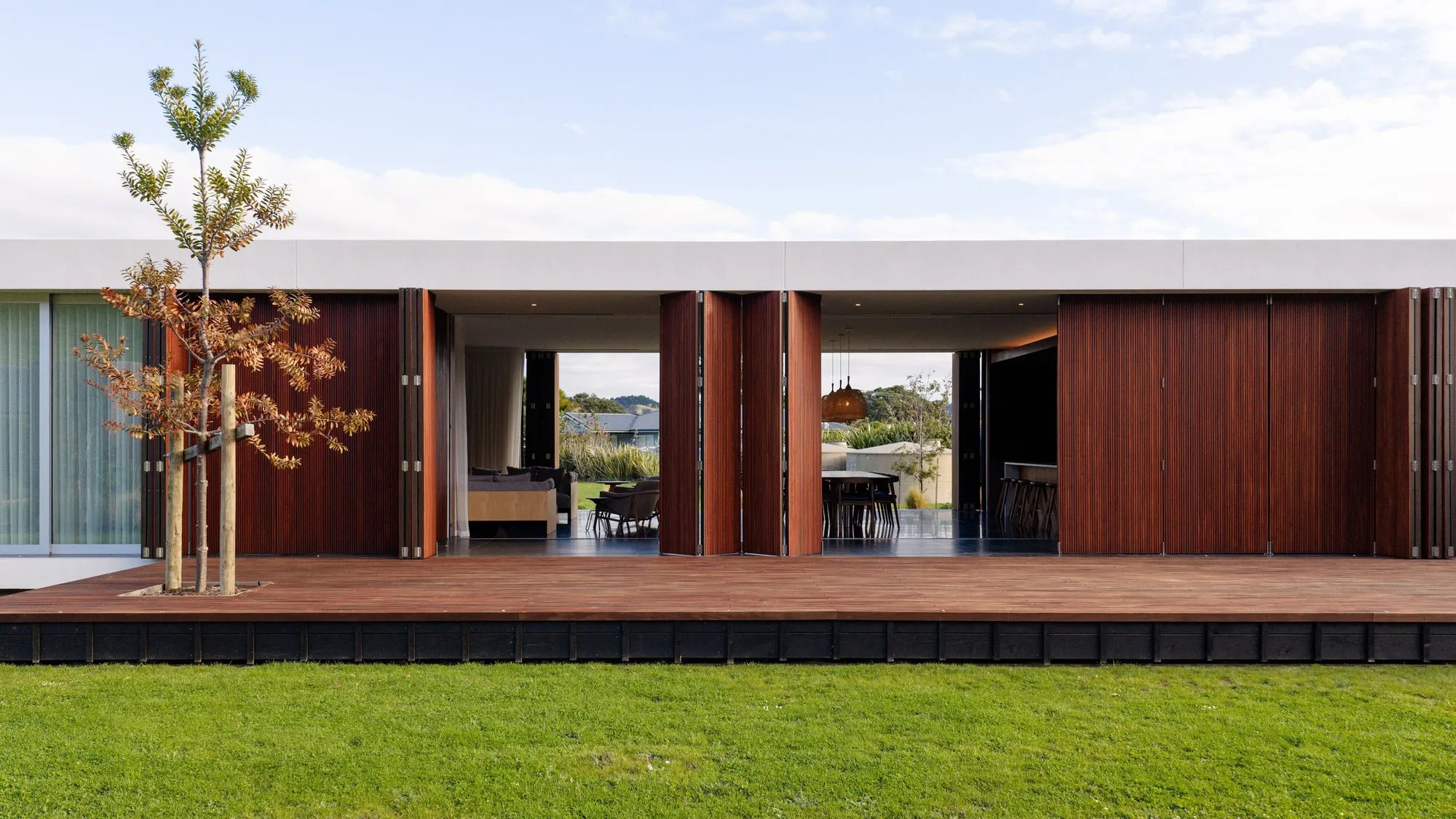 Long timber facade with the living space opened to the lawn