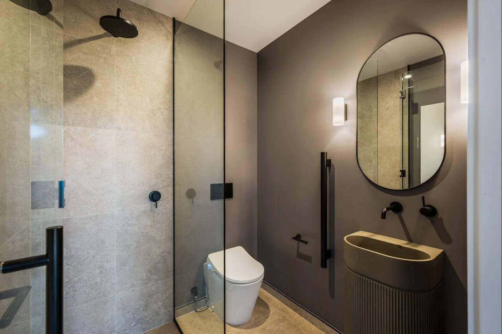 Bathroom with stone tiles, a curved mirror and a fluted basin